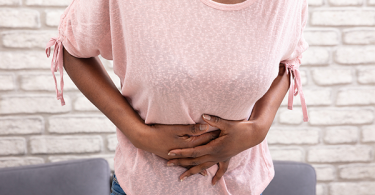 Young black woman holding stomach in pain from being on her period.