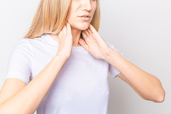 Woman holding thyroid glands on her neck