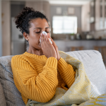 Woman blowing her nose at home