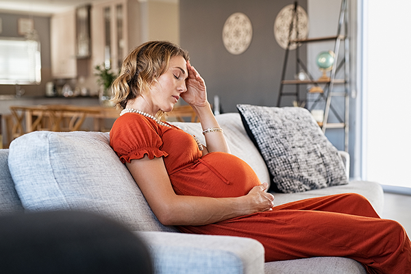Pregnant woman in pain sitting on sofa